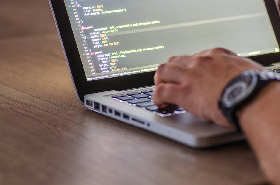 The image displays a close-up of a computer screen showing lines of code with syntax highlighting, including colors such as yellow, green, purple, and blue on a dark background. The code appears to be